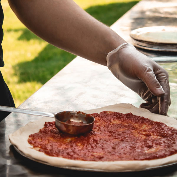 Maxwell's Wood Fired Catering Event Spreading Pizza Sauce